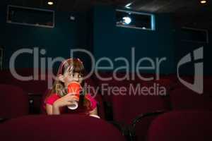 Girl having drink on seat in movie theater