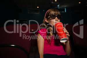 Girl wearing 3D glasses while having drink during movie