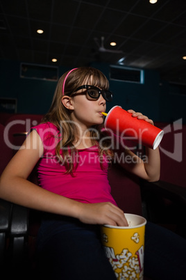 Girl wearing 3D glasses while having drink and popcorns during movie