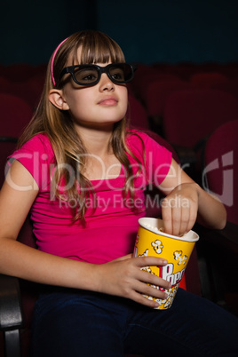 Girl wearing 3D glasses while having popcorns during movie