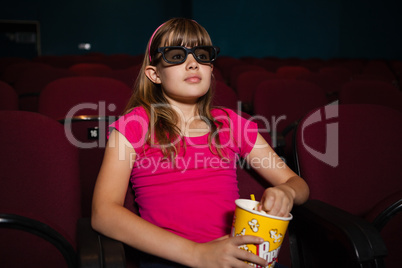 Girl using 3D glasses while having popcorns during movie