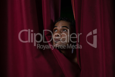 Ballet dancer peeking through a stage curtain