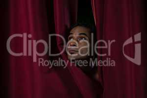 Ballet dancer peeking through a stage curtain