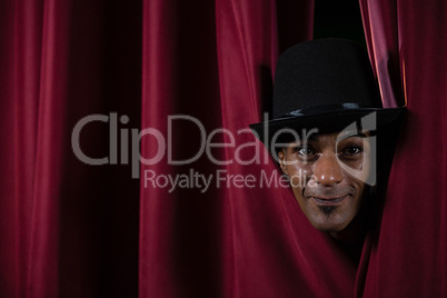 Ballet dancer peeking through a stage curtain