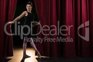 Ballerina posing in front of massive red stage curtain