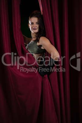 Female artist posing in front of massive red stage curtain