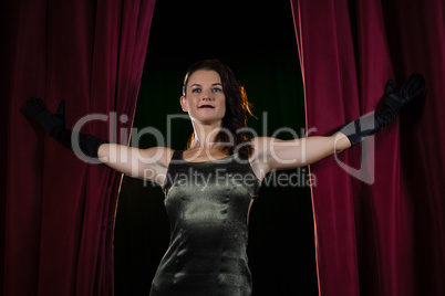 Female artist posing in front of massive red stage curtain
