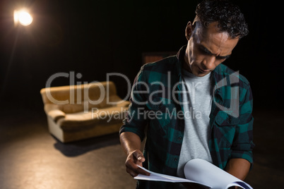 Actor reading their scripts on stage