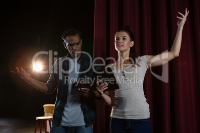 Actors rehearsing on stage while using digital tablet