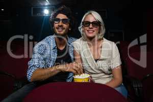 Couple having popcorn while watching movie in theatre