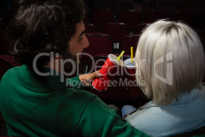 Couple toasting drinks while watching movie in theatre