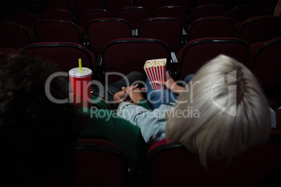 Couple having popcorn while watching movie in theatre