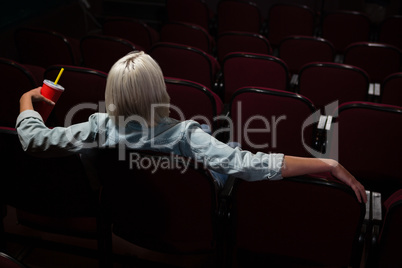 Woman having drinks while watching movie in theatre