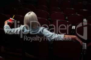 Woman having drinks while watching movie in theatre