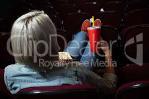 Woman having drinks while watching movie in theatre