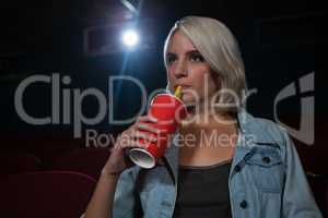 Woman having drinks while watching movie in theatre