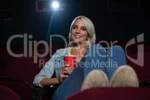 Woman having drinks while watching movie in theatre
