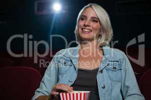 Woman having popcorn while watching movie in theatre