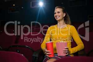 Woman having popcorn and drinks while watching movie in theatre