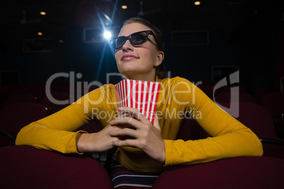 Woman having popcorn while watching movie in theatre