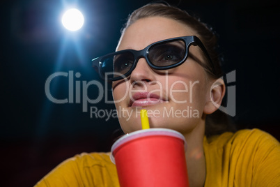 Woman having drinks while watching movie in theatre