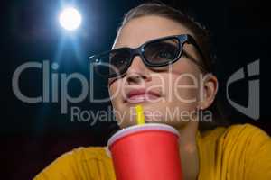 Woman having drinks while watching movie in theatre