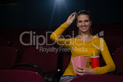 Woman having popcorn and drinks while watching movie in theatre