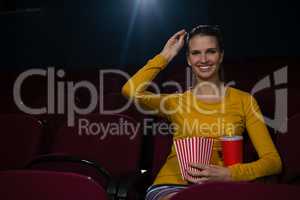 Woman having popcorn and drinks while watching movie in theatre