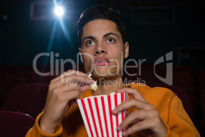 Man having popcorn while watching movie in theatre