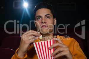 Man having popcorn while watching movie in theatre