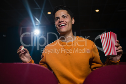 Man having popcorn while watching movie in theatre