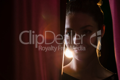 Ballet dancer peeking through a stage curtain