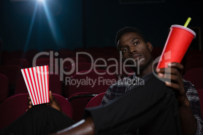 Man having popcorn and cold drink while watching movie