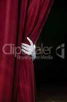 Hand in a white glove pulling curtain away