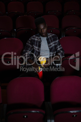 Man having cold drink and popcorn while watching movie
