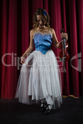 Female artist with violin standing on stage