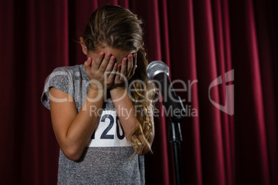 Girl covering her face with hand on stage