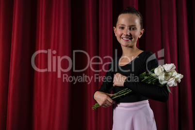 Ballerina posing with flower bouquet on stage