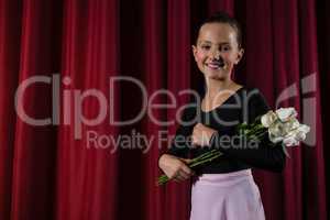 Ballerina posing with flower bouquet on stage
