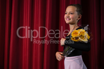 Ballerina posing with flower bouquet on stage