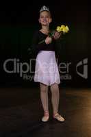 Ballerina posing with flower bouquet on stage