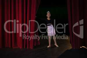 Ballet dancer peeking through a stage curtain