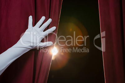 Hand in a white glove pulling curtain away