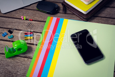 High angle view of smartphone on files with office supplies