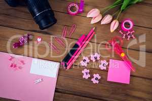 Overhead view of office supplies with camera and artificial tulip flowers