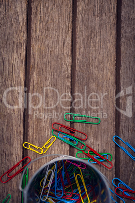 Overhead view of colorful paper clips by container