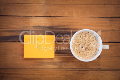 Overhead view of adhesive notes by coffee cup