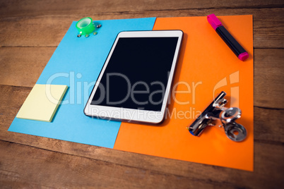 High angle view of digital tablet on papers with office supply