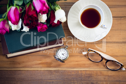 Overhead view of eyeglasses by stopwatch and tea with books