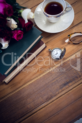 High angle view of eyeglasses by stopwatch and tea with books